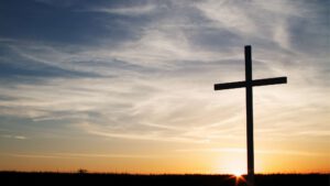a christian cross symbol silhouette at sunset sunrise.